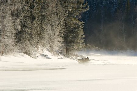young man posing on snowmobile at beautiful winter dayの写真素材