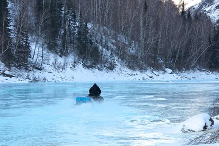 young man posing on snowmobile at beautiful winter dayの写真素材