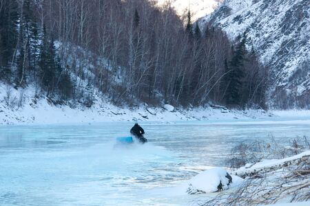 young man posing on snowmobile at beautiful winter dayの写真素材