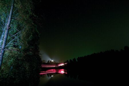 Driving a car on a night road in a forest with a long exposureの写真素材