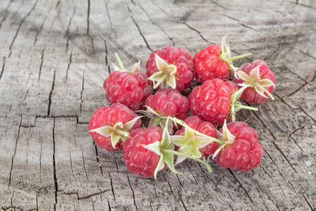 ripe raspberries with leaves on a wooden background