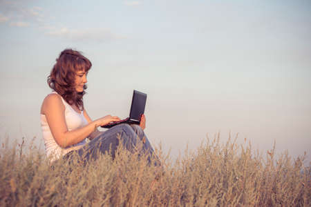 Girl with a computer on natureの写真素材