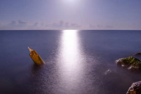 moonlit path on the sea and on the shore of large stonesの写真素材
