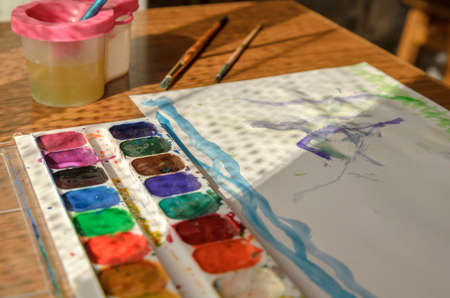 paints paintbrush and drawing lie on the tableの写真素材