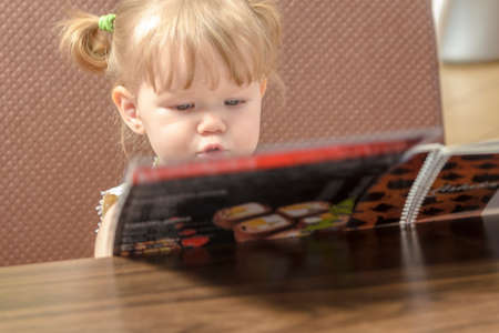 child in a restaurant looking menus and make a reservationの写真素材