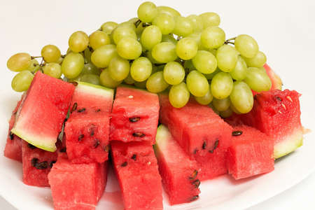 ripe sliced watermelon into slices and white grapesの写真素材