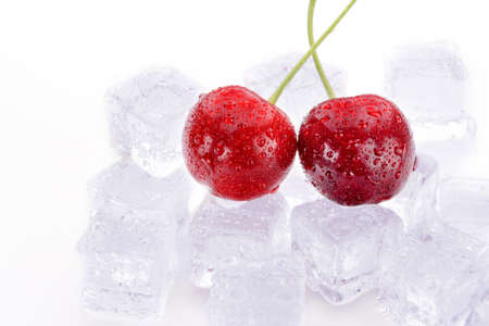 Two cherry berries lie on ice cubesの写真素材