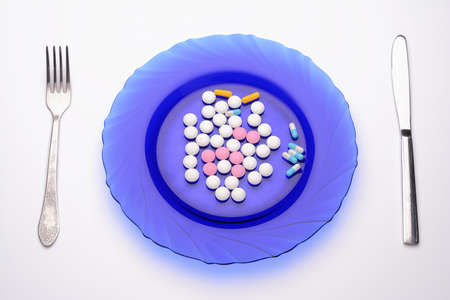 vitamin pills lying on a plate and cutlery are nearの写真素材