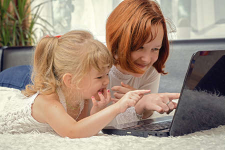 the children lying looking and laptopの写真素材