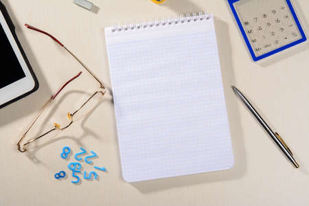 notebook glasses pen tablet and a calculator are on the table