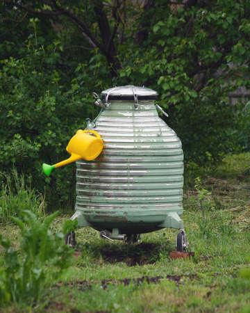a barrel of water and a watering can in the country for watering