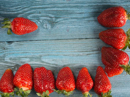 a lot of ripe strawberries lies on a blue wooden surfaceの写真素材