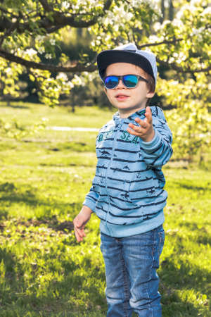 Child blonde 3-4 years in blue with hat and sunglasess askingの写真素材