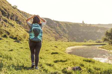 Traveler Woman with backpack looking landscape view at nature green field at sunset, tourism conceptの写真素材