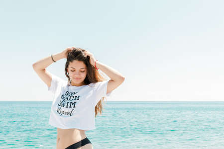 Relaxed woman enjoying sun, freedom and life on beautiful beach in sunshine. Young lady feeling free, relaxed and happy. Concept of vacations, freedom, happiness, enjoyment and well being.のeditorial素材