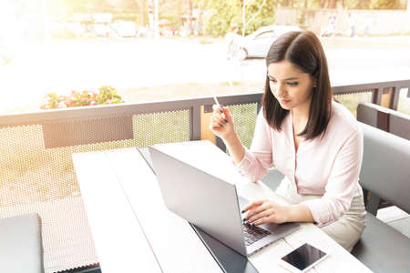 Image of young woman using laptop while sitting at cafe.の写真素材