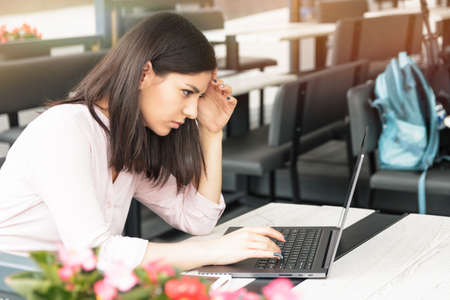 Very concentrated european woman looking into laptop in cafe