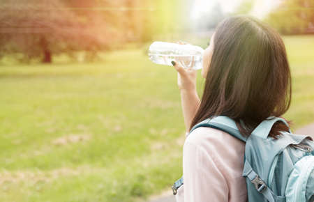 Woman drinking water outdoors in sunset in summer timeの写真素材