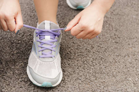 Girl lacing her shoes before running outdoors, workout wellness conceptの写真素材