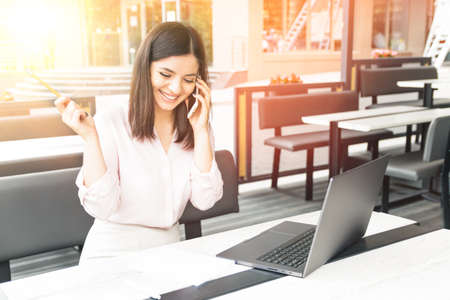 Businesswoman talking on phone in office or in a cafeの写真素材