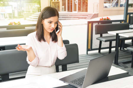 Businesswoman talking on phone in office or in a cafeの写真素材