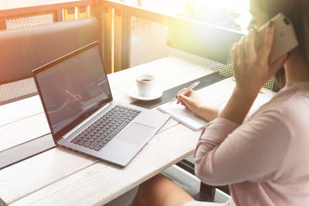 Businesswoman talking on phone in office or in a cafeの写真素材