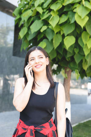 Attractive brunette businesswoman talking on mobile phone with client in the streetの写真素材