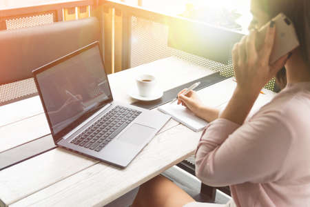 Businesswoman talking on phone in office or in a cafeの写真素材