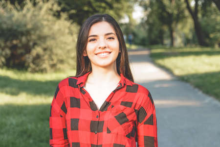 Happy woman in a red plaid shirt smiling in the park.のeditorial素材