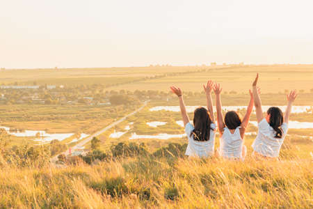 Group of three girls enjoying the sunset on a hill at countrysideの写真素材