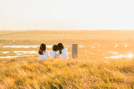 Group of three girls enjoying the sunset on a hill at countrysideの写真素材