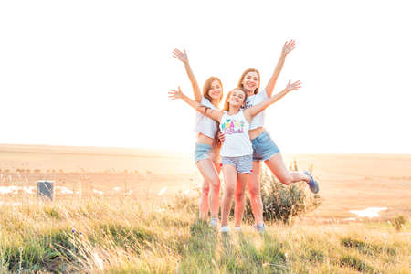 ETULIA, MOLDOVA - AUGUST 03, 2018: Group of three girls enjoying the sunset on a hill at countryside, jumping and smilingのeditorial素材