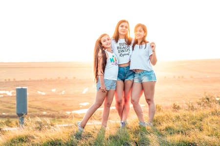 ETULIA, MOLDOVA - AUGUST 03, 2018: Group of three girls enjoying the sunset on a hill at countryside, jumping and smilingのeditorial素材