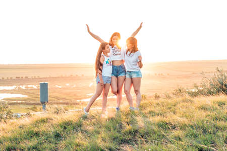 ETULIA, MOLDOVA - AUGUST 03, 2018: Group of three girls enjoying the sunset on a hill at countryside, jumping and smilingのeditorial素材