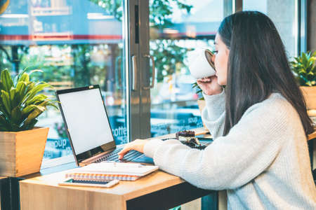 Side view of a woman working on laptop and drinking coffee at the same time - People conceptの写真素材