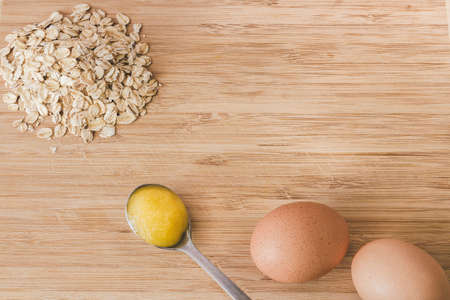 Raw oatmeal with ingredients honey and egg.の写真素材