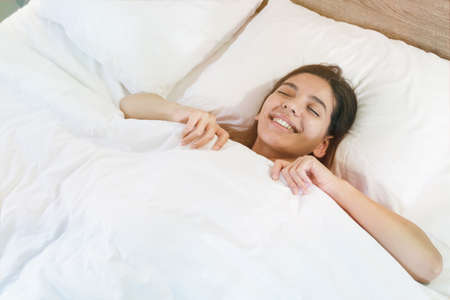 top view of an attractive young woman sleeping in bed, white sheetsの写真素材