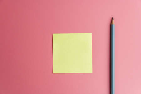 one yellow sticky note reminder and a pencil on a red background