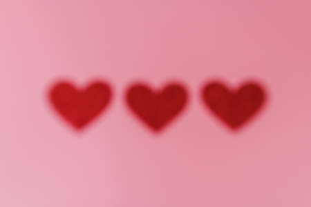 Three red heart shape figures out of focus on the background.の写真素材