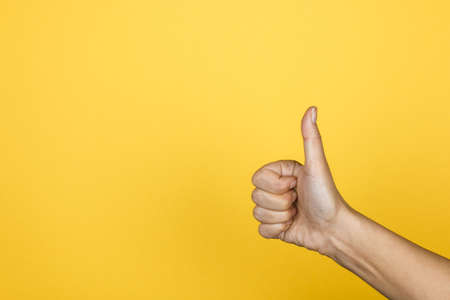 Hand of client show thumb up on yellow background, satisfaction concept, copy space for design.の写真素材