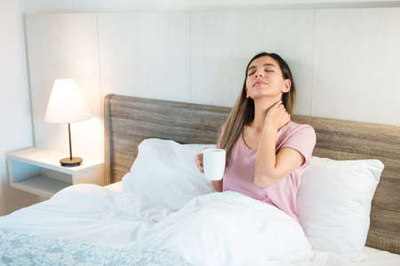 attractive woman with eyes closed holding a cup of coffee or tea. woman relaxing after a hard dayの写真素材