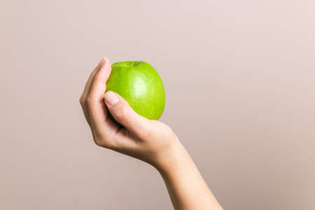 closeup female hand holding green apple, healthy life and food. diet conceptの写真素材