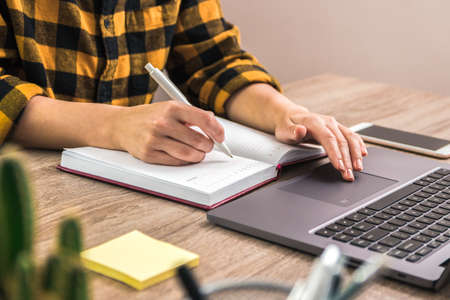 the study is power. close up hands of a businesswoman, student or freelancer in yellow shirt making...