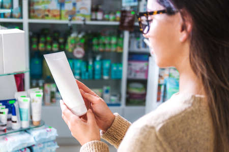 close up view woman in store holding a white jar reading the label. be careful what you buyの写真素材