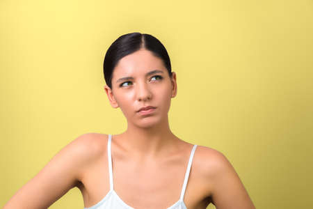 am i beautiful. beauty woman thinking and looking up isolated on yellow background