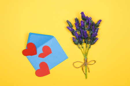 womans day card. lavender twig and blue envelope with red hearts on yellow background