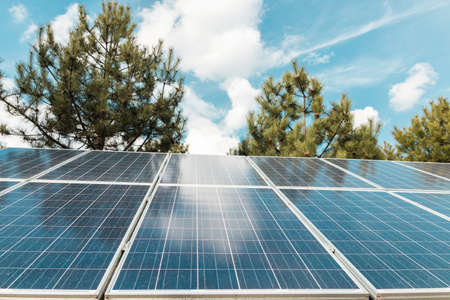 solar panel over a blue sky and green trees. ecological alternative energy productionの写真素材