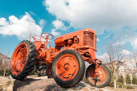old red tractor on farm over blue sky with cloudsの写真素材