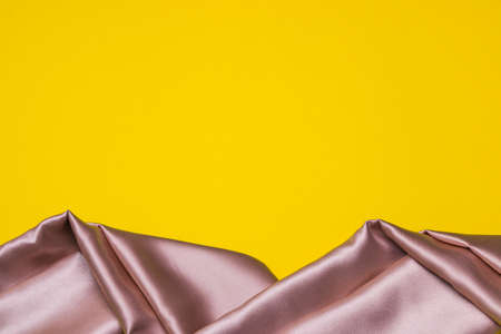 pink silk fabric against yellow background with copy space.の写真素材