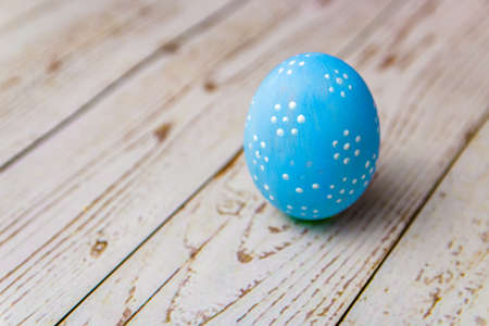 one blue hand painted egg with pattern on light colored wooden table. easter concept for 2020.の写真素材